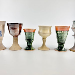 May include: Six ceramic goblets with various designs and colours. The goblets are all different shapes and sizes, and some have a painted design.