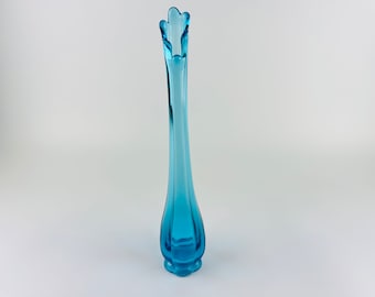 Pode incluir: Um vaso de vidro turquesa, alto e fino. O vaso tem um topo alargado com um design em forma de pétala e uma base arredondada. O vaso tem aproximadamente 30 cm de altura e é um item decorativo.