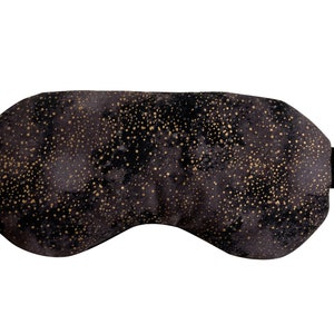 K&ouml;nnte beinhalten: Schwarze Schlafmaske mit goldfarbenem Glitzermuster. Die Maske hat ein elastisches Band.