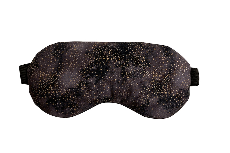 K&ouml;nnte beinhalten: Schwarze Schlafmaske mit goldfarbenem Glitzermuster. Die Maske hat ein elastisches Band.