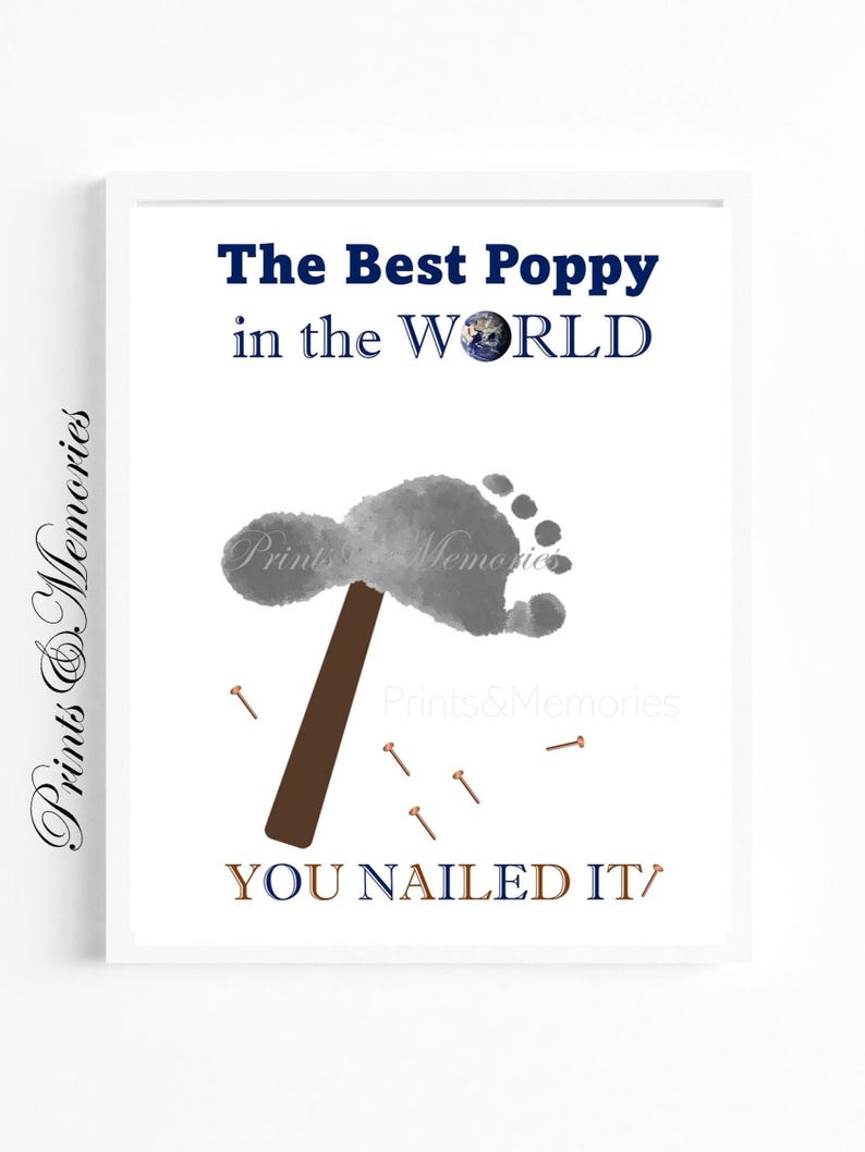 May include: Framed print with the text "The Best Poppy in the WORLD" and "YOU NAILED IT". It features a grey footprint, a brown hammer, and small nails. The print has the words "Prints & Memories" in the corners.
