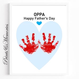 May include: A framed print with a white border. The artwork features red handprints forming a heart shape over a light blue heart. The text "OPPA Happy Father's Day" is above the heart, with a blue heart icon.