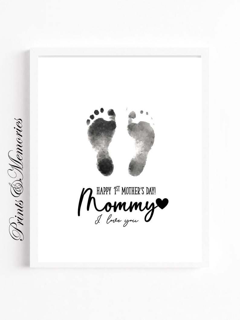Pu&ograve; includere: Stampa ad acquerello in bianco e nero di due impronte di piedi di bambino con il testo "Happy 1st Mother's Day! Mommy I love you" e un piccolo cuore nero.