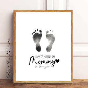Pu&ograve; includere: Una stampa ad acquerello in bianco e nero di due impronte di piedi di bambino con il testo "Happy 1st Mother's Day! Mommy I love you" e un cuore nero.