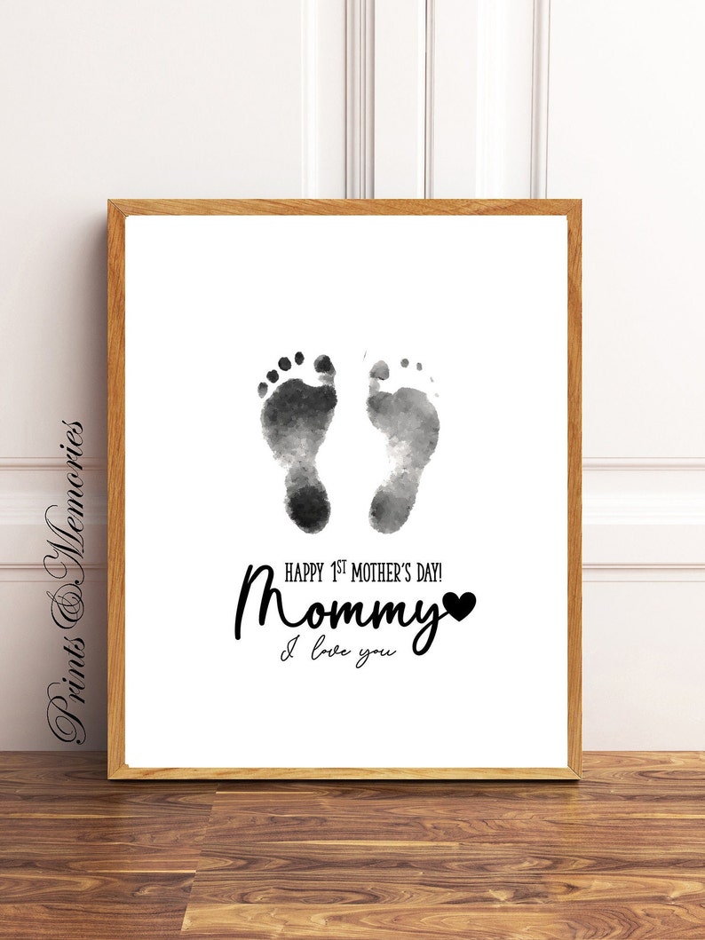 Pu&ograve; includere: Una stampa ad acquerello in bianco e nero di due impronte di piedi di bambino con il testo "Happy 1st Mother's Day! Mommy I love you" e un cuore nero.