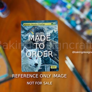 May include: A custom-made Magic: The Gathering card with a portrait of a man and a white wolf. The card reads "MADE TO ORDER" and "REFERENCE ONLY IMAGE NOT FOR SALE". The card is on a wooden surface.