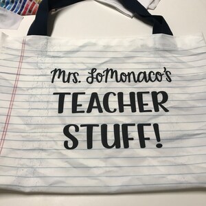 May include: White canvas tote bag with black handles and the text "Mrs. SoMonaco's Teacher Stuff!" printed on it.