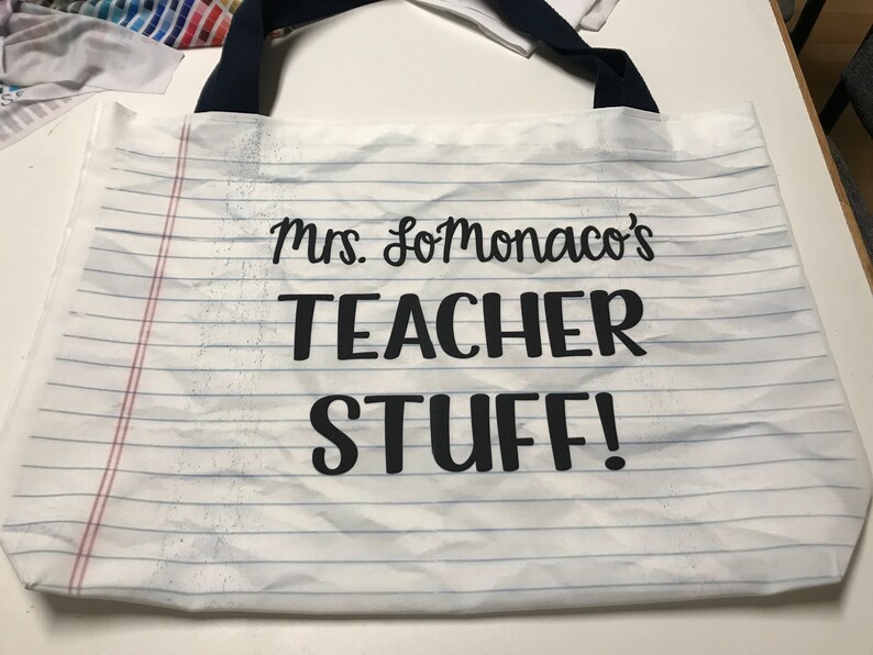 May include: White canvas tote bag with black handles and the text "Mrs. SoMonaco's Teacher Stuff!" printed on it.