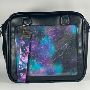 May include: Black faux leather satchel bag with a clear plastic window displaying a galaxy print. The bag has a detachable strap with a galaxy print.
