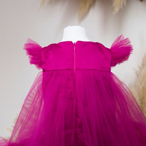 Peut inclure: Une robe en tulle magenta avec un corsage en satin et des manches bouffantes. La robe a une fermeture &eacute;clair dans le dos.