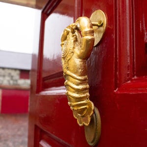 Gold lobster shaped door knocker on a red door