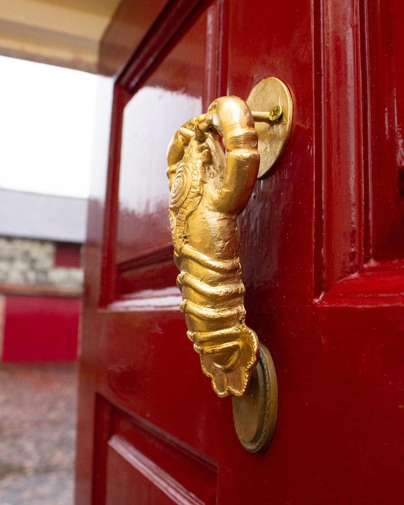 Gold lobster shaped door knocker on a red door