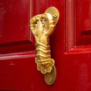 Gold lobster-shaped door knocker on a red door