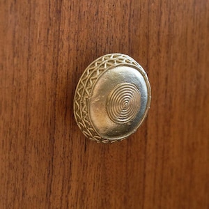 May include: A gold-toned cabinet knob with a decorative spiral design.