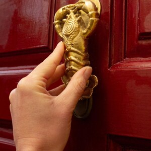 Gold lobster shaped unique door knocker on a red door