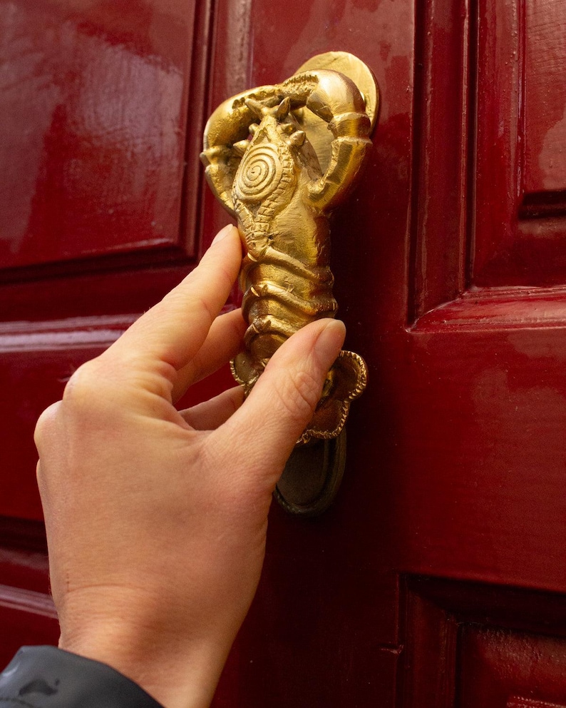 Gold lobster shaped unique door knocker on a red door
