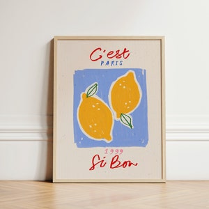 May include: A framed print with a blue background and two yellow lemons. The text "C'est Paris" is at the top of the print, and the text "1999 Si Bon" is at the bottom.