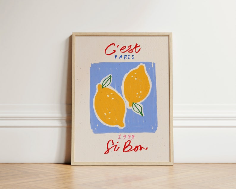 May include: A framed print with a blue background and two yellow lemons. The text "C'est Paris" is at the top of the print, and the text "1999 Si Bon" is at the bottom.