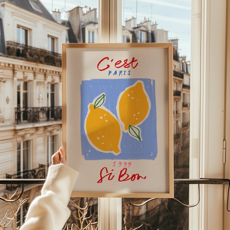 May include: A framed print with a blue background and two yellow lemons. The text on the print reads "C'est Paris 1999 Si Bon."