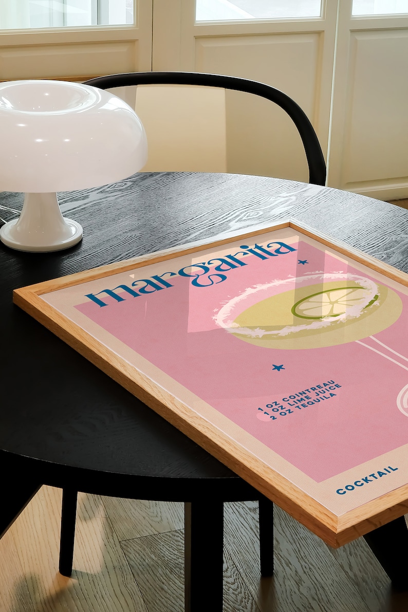Peut inclure: Une affiche encadr&eacute;e avec un fond rose et une illustration bleue et blanche d'un cocktail margarita. Le texte "margarita" est en lettres bleues et blanches. Les ingr&eacute;dients sont list&eacute;s sous l'illustration&nbsp;: 1&nbsp;oz de Cointreau, 1&nbsp;oz de jus de citron vert, 2&nbsp;oz de tequila. Le mot "COCKTAIL" est en lettres bleues en bas de l'affiche.