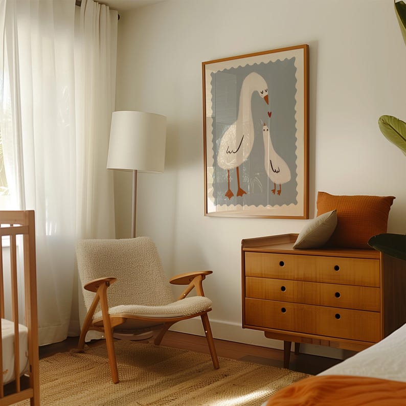 K&ouml;nnte beinhalten: Ein helles Kinderzimmer mit einem gerahmten Druck von zwei G&auml;nsen, einer Holzkommode, einem gem&uuml;tlichen Stuhl und einem Kinderbett. Das Kunstwerk zeigt eine Muttergans und ein G&auml;nsek&uuml;ken mit einem Herz. Der Raum hat eine neutrale Farbpalette mit warmen Holzt&ouml;nen.