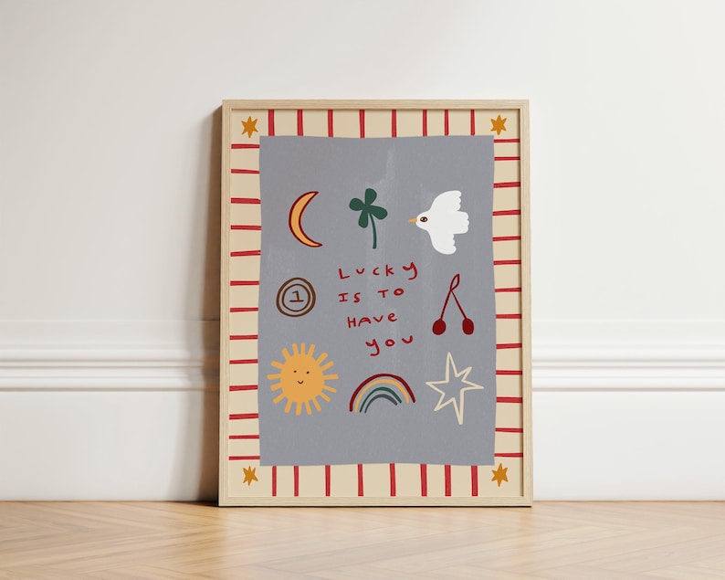 May include: A framed print with a gray background and red and white stripes. The print features a variety of illustrations including a sun, a rainbow, a four-leaf clover, a bird, a cherry, a star, and a circle with the number one. The text "Lucky is to have you" is written in red.