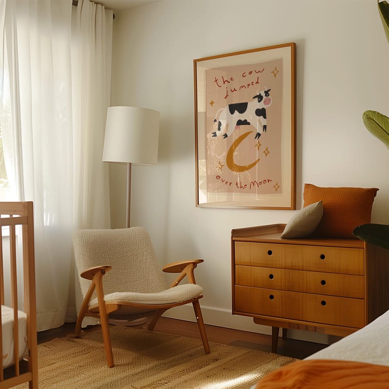 May include: A cozy nursery scene featuring a wooden crib, a mid-century modern chair, and a wooden dresser. A framed print with a cow jumping over the moon hangs on the wall. The room is bathed in natural light from sheer curtains.