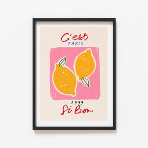 May include: A framed print with a pink background and two yellow lemons. The text "C'est Paris 1999 Si Bon" is written in red and blue.