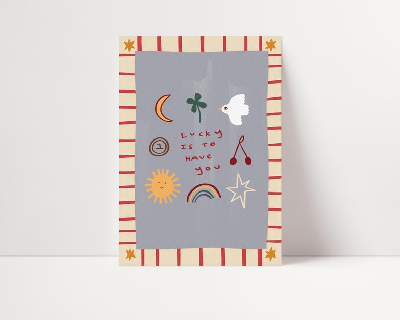 May include: A light blue card with red and white stripes around the border. The card has a variety of illustrations including a crescent moon, a four-leaf clover, a bird, a cherry, a sun, a rainbow, and a star. The text on the card reads "Lucky is to have you".