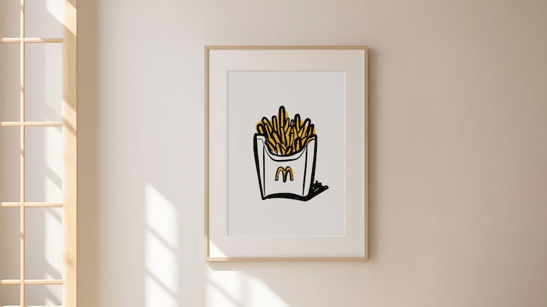 K&ouml;nnte beinhalten: Ein gerahmter Druck einer Schwarzwei&szlig;illustration einer Schachtel Pommes mit einem gelben 'M'-Logo. Die Pommes sind gelb und die Schachtel ist wei&szlig;.
