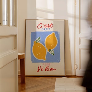 May include: A framed print with a blue background and two yellow lemons. The text "C'est Paris" is written in red at the top of the print. The text "1999 Si Bon" is written in red at the bottom of the print.