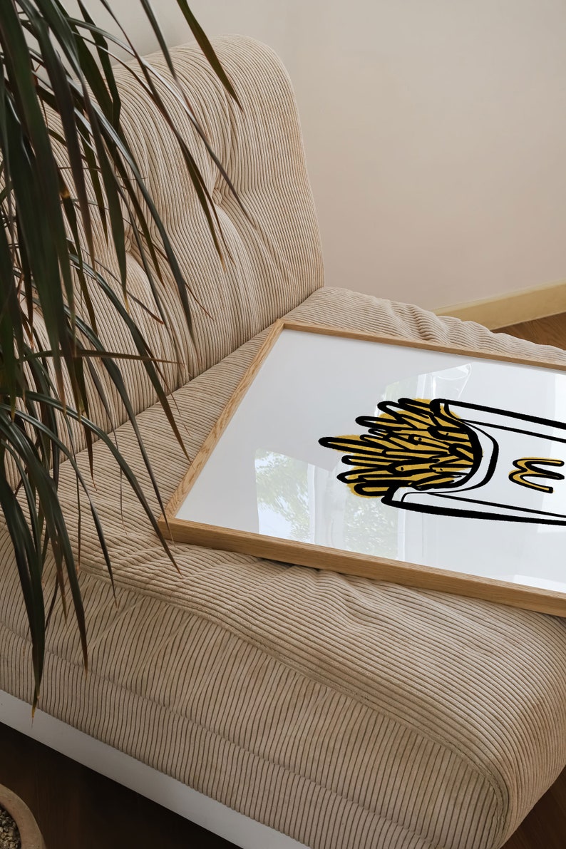 K&ouml;nnte beinhalten: Eine gerahmte Illustration einer gelben und wei&szlig;en Cartoon-Zeichnung einer Schachtel Pommes Frites. Die Schachtel tr&auml;gt den Buchstaben "M".