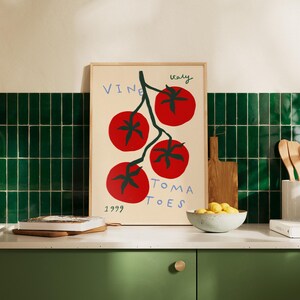 May include: A framed print with a white background and a stylised illustration of a vine with red tomatoes. The text "Vine Tomatoes" is written in black and the text "Italy 1999" is written in black at the bottom of the print.