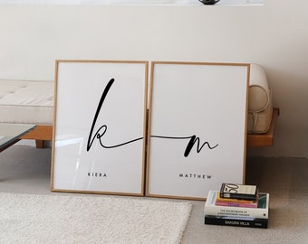 May include: Two framed prints with black calligraphy on a white background. The left print features the letter "k" with the name "Kiera" below it. The right print features the letter "m" with the name "Matthew" below it.