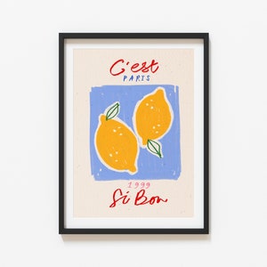 May include: A framed print with a blue background and two yellow lemons. The text "C'est Paris" is at the top of the print and "1999 Si Bon" is at the bottom.