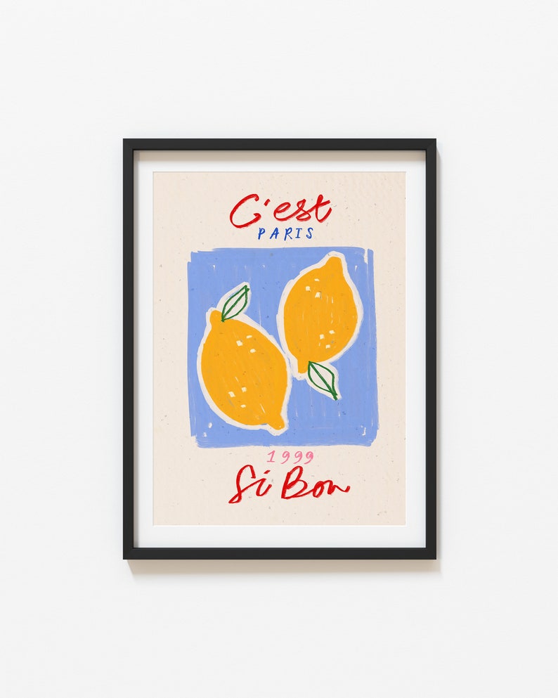 May include: A framed print with a blue background and two yellow lemons. The text "C'est Paris" is at the top of the print and "1999 Si Bon" is at the bottom.