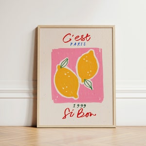 May include: A framed print with a pink background and two yellow lemons. The text "C'est Paris" is at the top of the print, and the text "1999 Si Bon" is at the bottom.