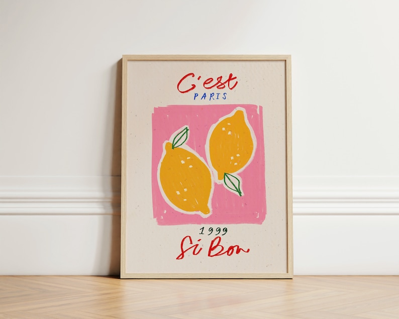 May include: A framed print with a pink background and two yellow lemons. The text "C'est Paris" is at the top of the print, and the text "1999 Si Bon" is at the bottom.
