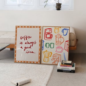 May include: Two framed prints on a white rug. The print on the left has the text "Coffee is always a good idea." The print on the right has a colorful illustration of coffee makers and mugs.