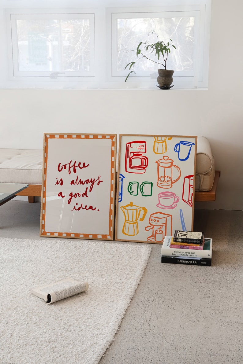 May include: Two framed prints on a white rug. The print on the left has the text "Coffee is always a good idea." The print on the right has a colorful illustration of coffee makers and mugs.