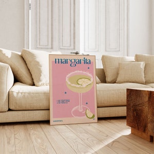 Peut inclure: Une affiche rose et blanche avec le texte "margarita" en bleu et blanc. L'affiche repr&eacute;sente un verre &agrave; cocktail avec un quartier de citron vert et un fond rose. Le texte "1 oz Cointreau, 1 oz Jus de citron vert, 2 oz Tequila" est imprim&eacute; sous le verre. L'affiche comprend &eacute;galement le texte "Cocktail" et une petite &eacute;toile.