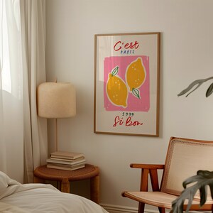 May include: A framed print with a pink background and two yellow lemons. The text on the print reads "C'est Paris 1999 Si Bon".