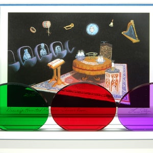 May include: Three colored, oval-shaped glass pieces in green, red, and purple, with a framed illustration of a haunted mansion scene. The green glass has the text "Disney's Haunted Mansion". The red glass has the text "Leota's Room".