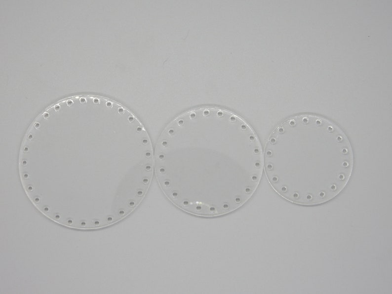 May include: Three clear, circular acrylic bases for crafting projects. Each base has a series of evenly spaced holes around the perimeter. The sizes vary, with the largest measuring approximately 8 inches in diameter, and the smallest about 4 inches.