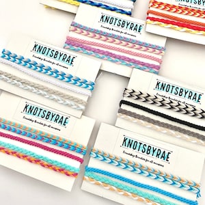 May include: Assortment of colourful friendship bracelets with the text "KNOTSBYRAE Friendship Bracelets for all occasions" on each card.
