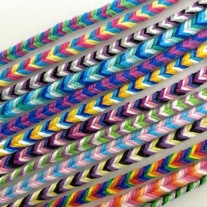 Peut inclure: Gros plan sur plusieurs bracelets d'amitié colorés tissés en chevron. Les bracelets sont faits de cordons fins et tressés de différentes couleurs, notamment rose, bleu, vert, jaune, blanc et noir.