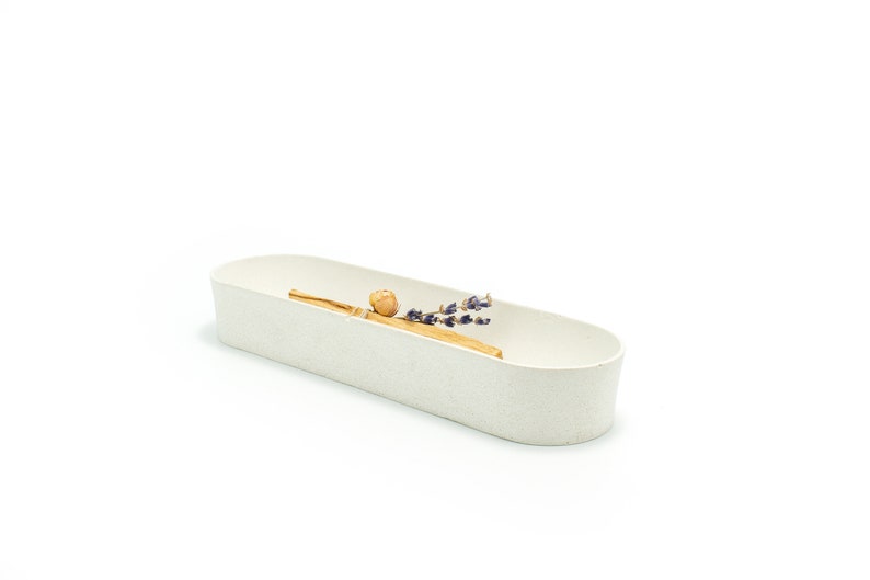 Puede incluir: Un plato ovalado de cer&aacute;mica blanca con una rama de lavanda seca y un palo de madera en su interior.