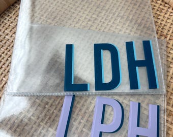 May include: Two clear rectangular plastic pouches. The top pouch features the dark blue and light blue letters LDH. The bottom pouch features the light purple and dark blue letters LPH. Both pouches have a smooth, transparent finish.