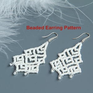 May include: A pair of white beaded earrings with a geometric design. The earrings are made with small white beads and have silver hooks. The earrings are on a gray background with white feathers.