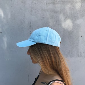 May include: A light blue baseball cap with a curved brim. The cap is made of a soft, cotton fabric.